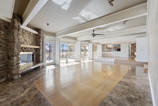 unfurnished living room featuring a fireplace, beamed ceiling, and ceiling fan with notable chandelier