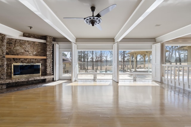 unfurnished living room featuring light wood-style floors, a stone fireplace, and a ceiling fan