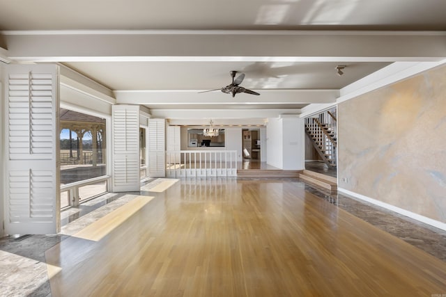 unfurnished living room featuring crown molding, stairway, beamed ceiling, and wood finished floors