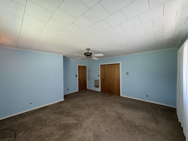 spare room featuring baseboards, ornamental molding, dark carpet, and a ceiling fan