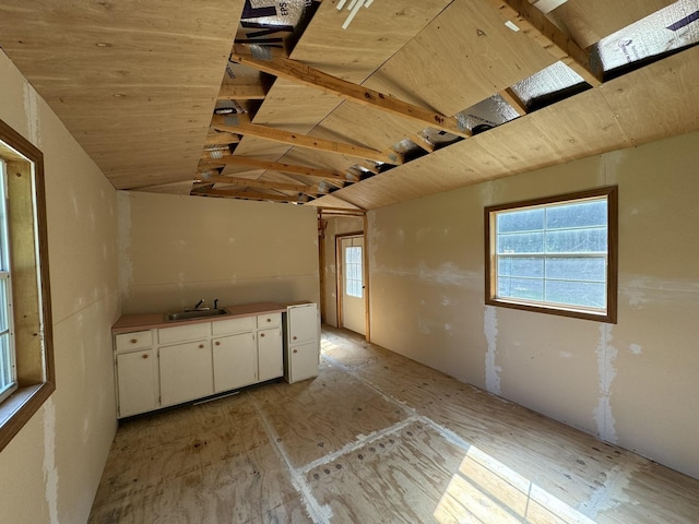 kitchen featuring lofted ceiling, white cabinetry, and a sink