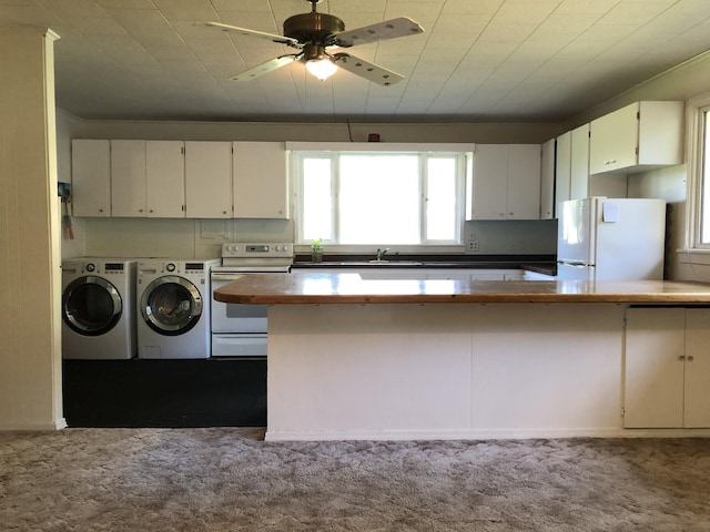 kitchen featuring white appliances, white cabinets, carpet, washer and dryer, and a sink