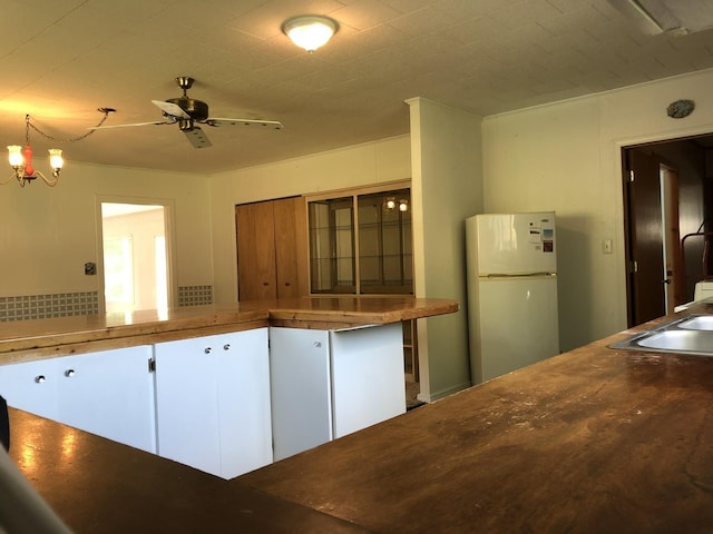 kitchen with ceiling fan, a sink, white cabinets, freestanding refrigerator, and pendant lighting