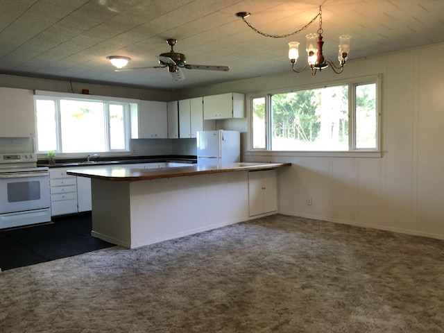 kitchen with a peninsula, white appliances, white cabinetry, and hanging light fixtures