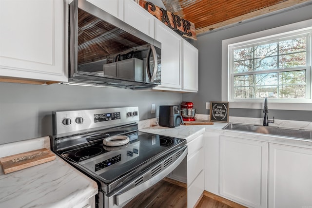 kitchen featuring appliances with stainless steel finishes, white cabinetry, a sink, and light stone counters