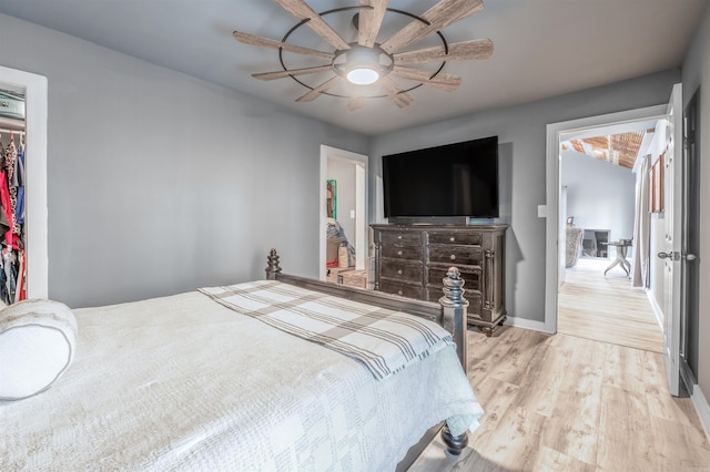 bedroom featuring a walk in closet, light wood finished floors, a closet, ceiling fan, and baseboards