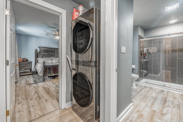 laundry room with light wood-style floors, laundry area, stacked washing maching and dryer, and a ceiling fan