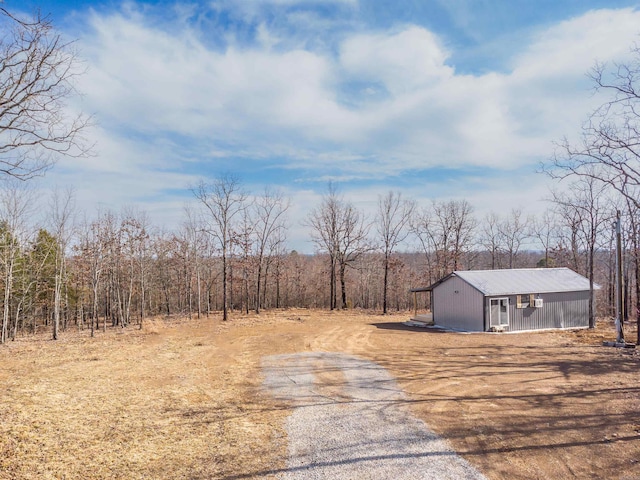 view of yard featuring driveway and a wooded view