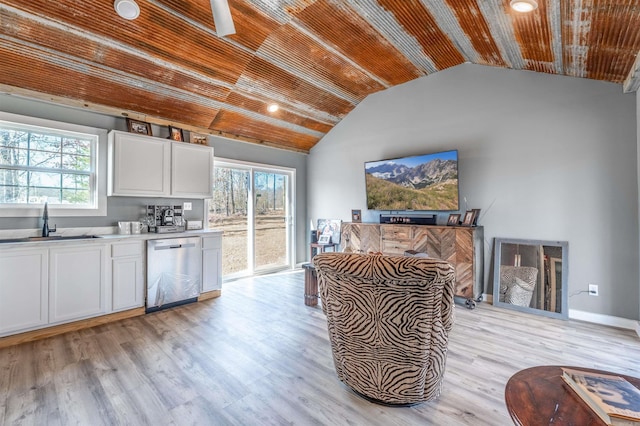 kitchen with a sink, wood ceiling, white cabinetry, light countertops, and stainless steel dishwasher