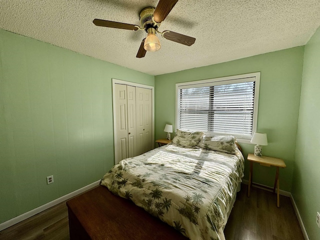 bedroom with dark wood-style floors, a textured ceiling, baseboards, and a closet