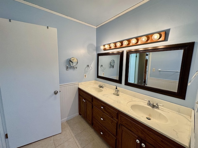 bathroom featuring crown molding, a wainscoted wall, a sink, and tile patterned floors