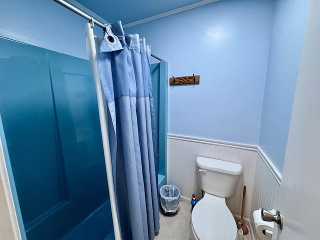 full bath featuring toilet, a wainscoted wall, tile patterned flooring, and curtained shower