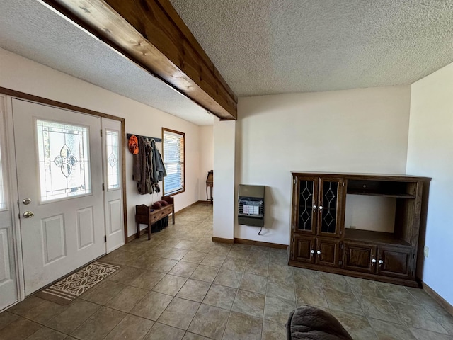 entryway featuring a textured ceiling, light tile patterned floors, baseboards, heating unit, and beamed ceiling