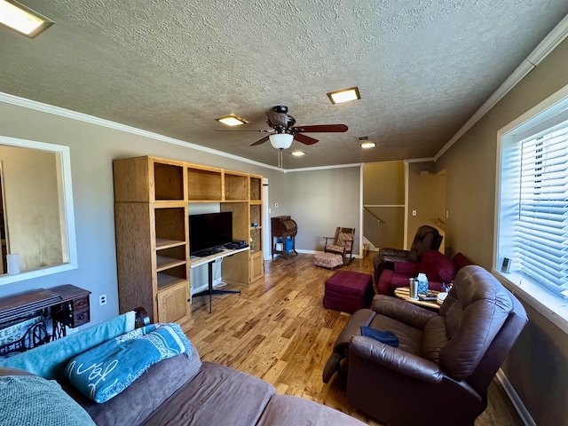 living room with ceiling fan, ornamental molding, a textured ceiling, and light wood-style floors