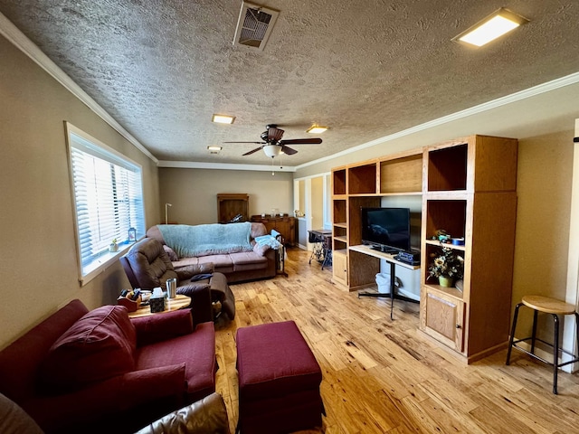 living room with visible vents, light wood-style flooring, ceiling fan, a textured ceiling, and crown molding