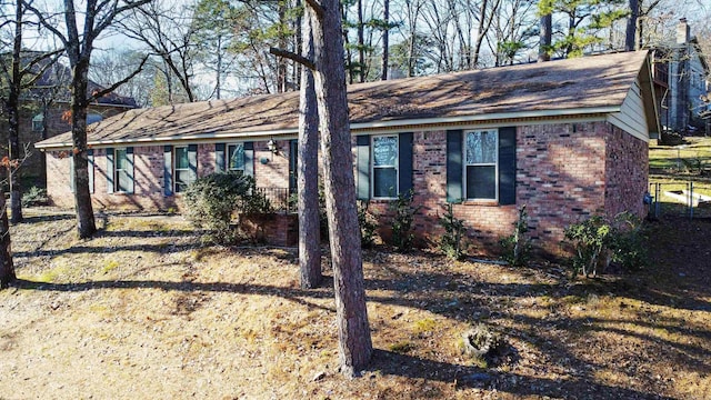 ranch-style house with a chimney and brick siding