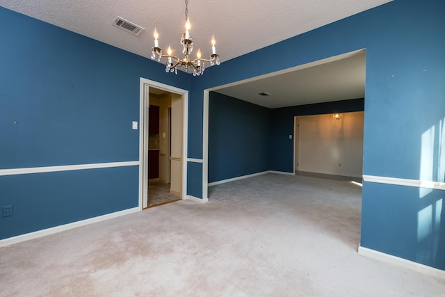 empty room featuring a textured ceiling, visible vents, baseboards, carpet, and an inviting chandelier