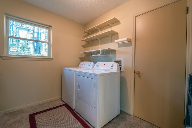 clothes washing area with a textured ceiling, laundry area, washing machine and dryer, and baseboards