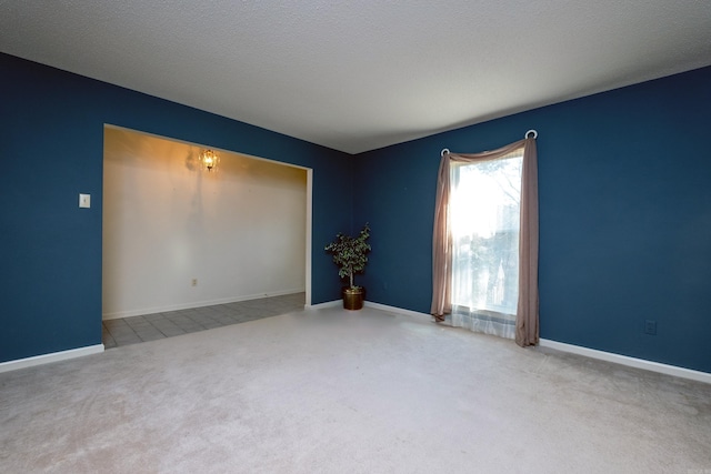 carpeted spare room with baseboards and a textured ceiling