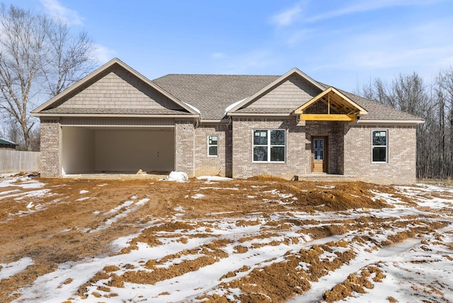 craftsman inspired home with a garage, brick siding, and a shingled roof