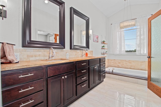 bathroom with vaulted ceiling, a garden tub, a sink, and double vanity