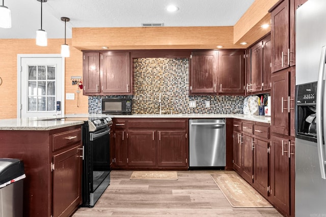 kitchen with visible vents, light wood-style flooring, appliances with stainless steel finishes, hanging light fixtures, and a sink