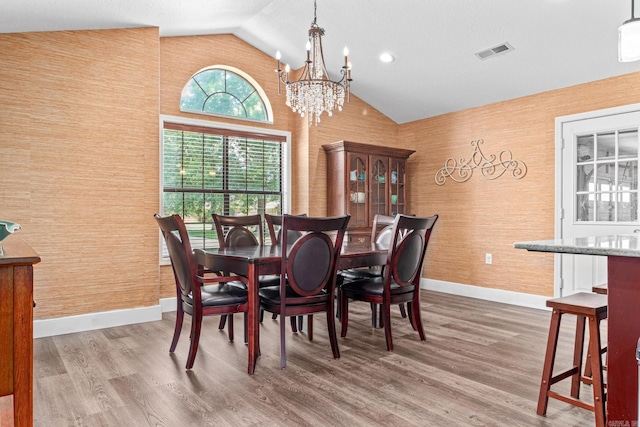 dining space with high vaulted ceiling, visible vents, wood finished floors, a chandelier, and baseboards