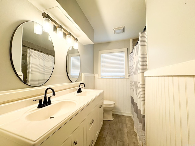 bathroom with wainscoting, a sink, visible vents, and wood finished floors