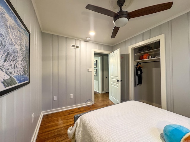 bedroom with dark wood-style floors, ornamental molding, visible vents, and a ceiling fan