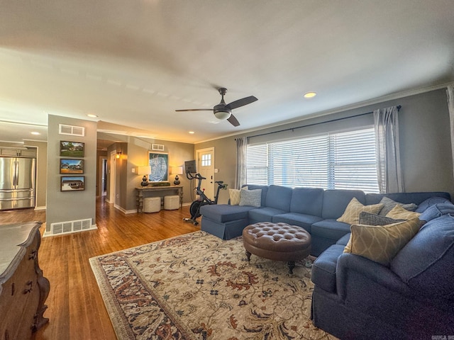 living room with visible vents, crown molding, baseboards, and wood finished floors