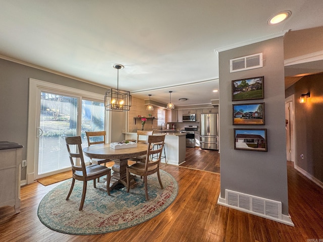 dining area with a chandelier, visible vents, dark wood finished floors, and ornamental molding