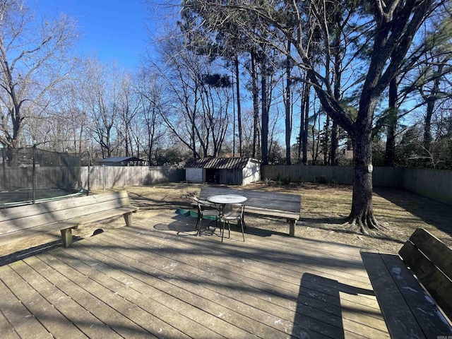 wooden deck with an outbuilding, a storage unit, outdoor dining area, and a fenced backyard