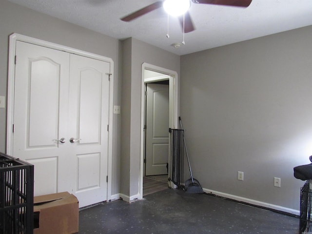 unfurnished bedroom with a closet, ceiling fan, finished concrete flooring, and baseboards