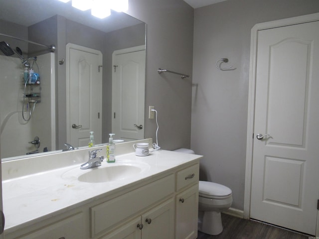 bathroom featuring toilet, wood finished floors, vanity, a shower, and a closet