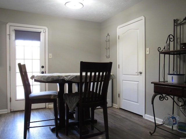 dining room featuring dark wood-style floors, baseboards, and a textured ceiling