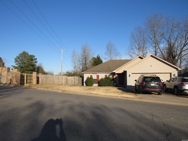 ranch-style home with a garage, driveway, and fence