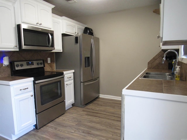 kitchen featuring stainless steel appliances, white cabinets, and a sink