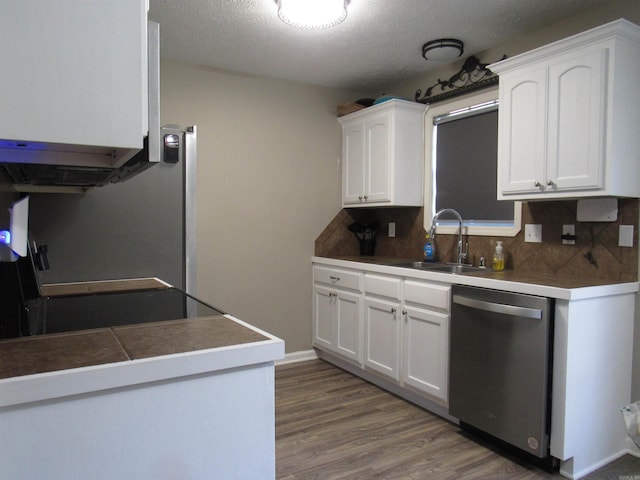 kitchen featuring backsplash, stainless steel dishwasher, white cabinets, a sink, and wood finished floors