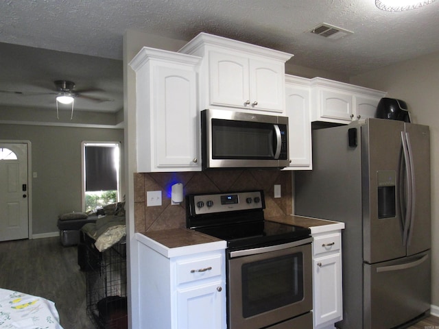 kitchen featuring stainless steel appliances, white cabinets, and visible vents