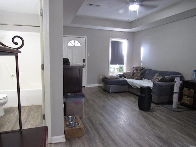 living area featuring dark wood finished floors, plenty of natural light, a raised ceiling, and visible vents