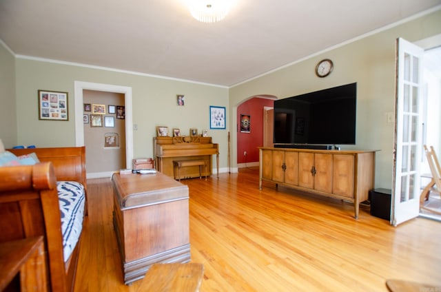 living area with arched walkways, light wood finished floors, baseboards, and crown molding