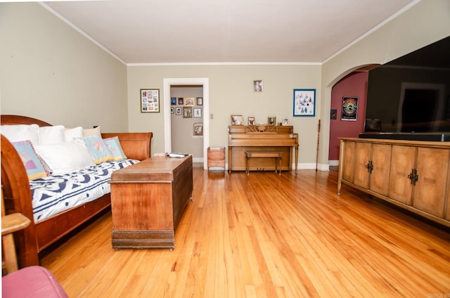 living area featuring arched walkways, baseboards, light wood-style flooring, and crown molding