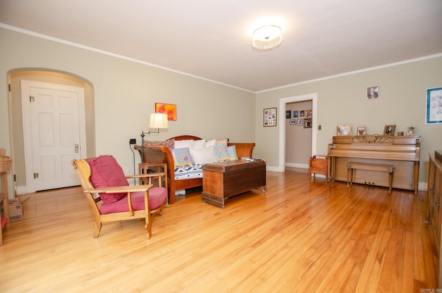 bedroom with light wood-style floors, baseboards, arched walkways, and crown molding