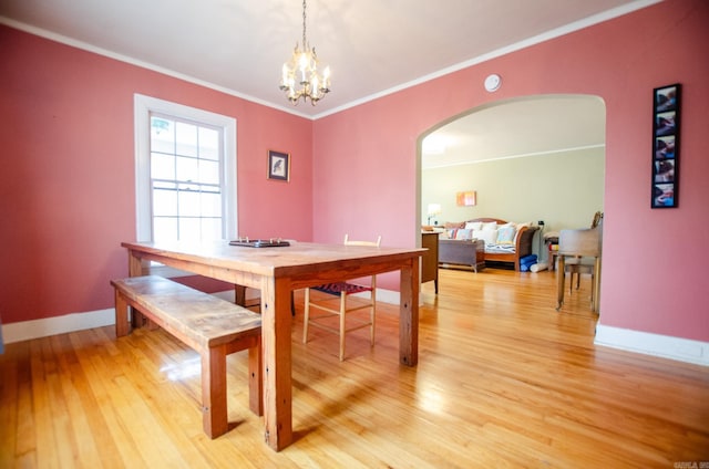 dining area with arched walkways, a chandelier, baseboards, ornamental molding, and light wood-type flooring