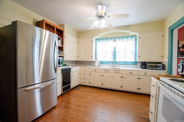 kitchen with stainless steel appliances, light countertops, light wood-style floors, white cabinetry, and a sink