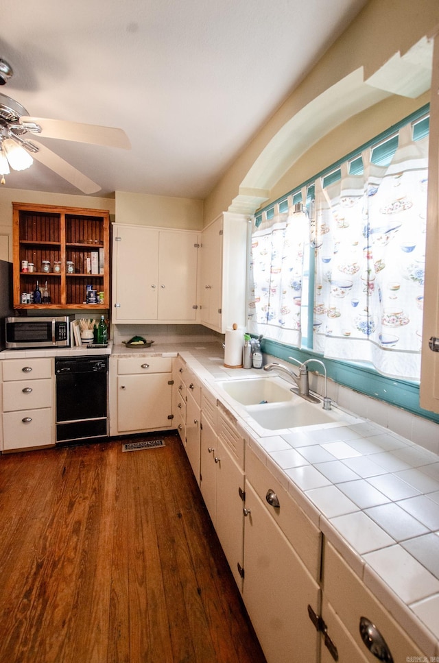 kitchen with tile counters, white cabinets, dishwasher, stainless steel microwave, and a sink