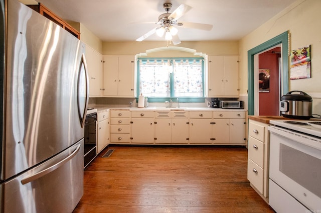 kitchen with white cabinets, light countertops, freestanding refrigerator, light wood finished floors, and white range with electric cooktop