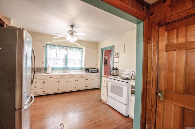 kitchen featuring white electric range, light countertops, freestanding refrigerator, and white cabinetry