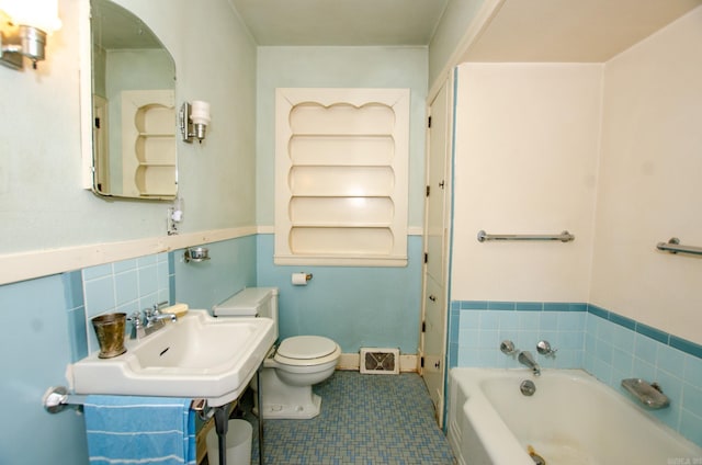 bathroom featuring baseboards, visible vents, toilet, a bath, and a sink