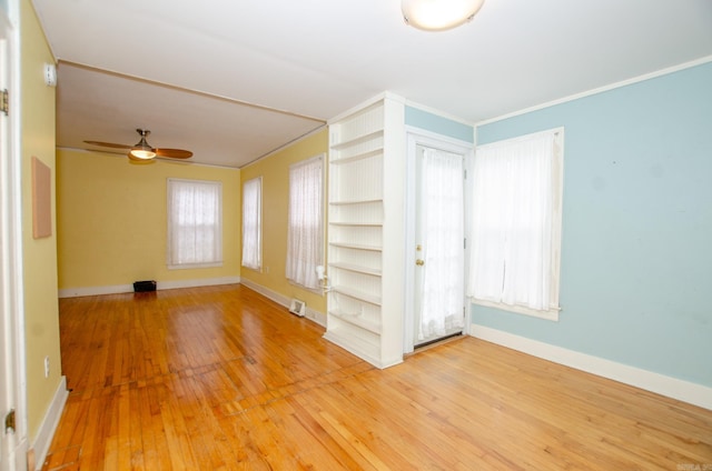 spare room featuring visible vents, baseboards, ceiling fan, wood finished floors, and crown molding